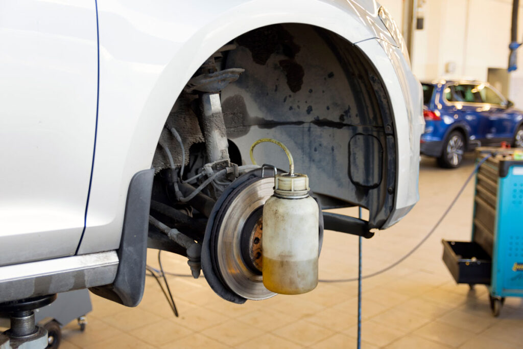 Car repair in a car service. Replacing brake fluid on a vehicle. The brake disc and a special tool against the background of a repair shop.