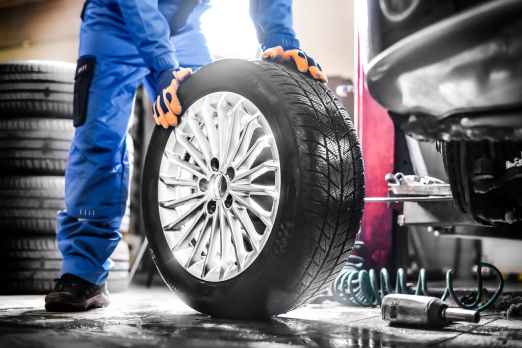 Car mechanic working in garage and changing wheel alloy tire in Ireland.